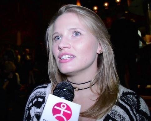 Natalia Rybicka na scenie teatralnej, w trakcie występu, z emocjonalnym wyrazem twarzy, oświetlona ciepłymi reflektorami.
