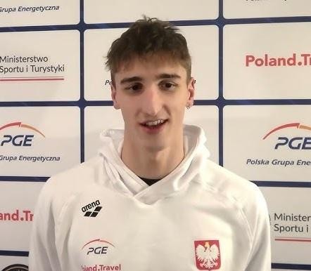 Ksawery Masiuk w trakcie wyścigu pływackiego, dynamicznie płynący stylem grzbietowym.