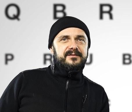 Arkadiusz Jakubik, wokalista zespołu Dr Misio, podczas energicznego występu na scenie, śpiewający do mikrofonu, z dynamicznym oświetleniem koncertowym.