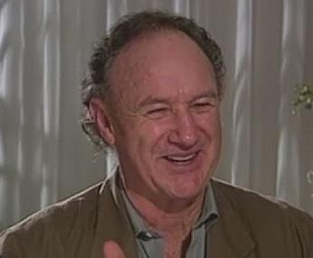 Młody Gene Hackman podczas zajęć aktorskich lub wykładu z dziennikarstwa, symbolizujący początki jego edukacji.