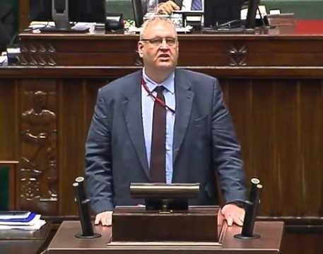Bogdan Roman Święczkowski w trakcie wystąpienia publicznego, z widocznym zdecydowaniem i autorytetem.