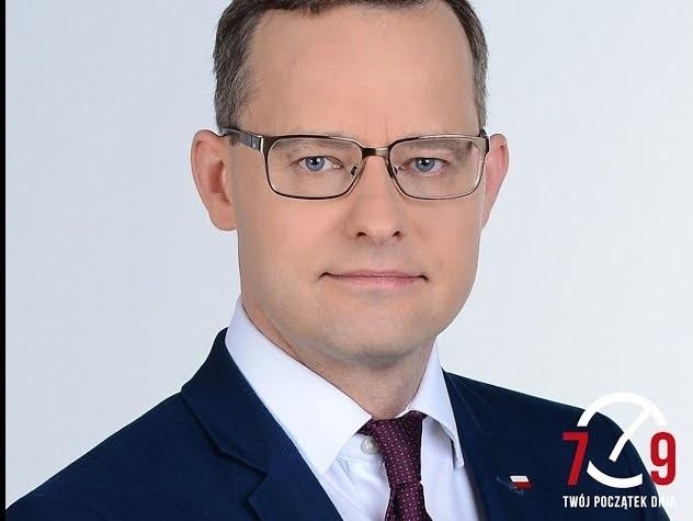 Marcin Romanowski przemawiający na forum publicznym, gestykulujący z przekonaniem.