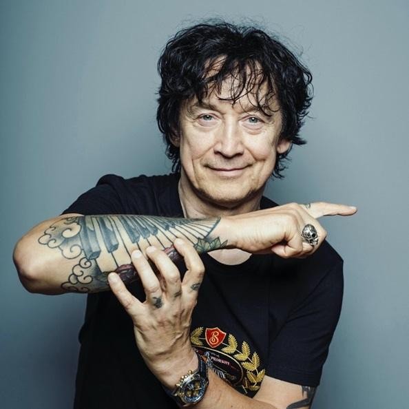 Jan Borysewicz podczas warsztatów muzycznych z młodymi adeptami Fundacji Akademia Jana Borysewicza, w tle instrumenty muzyczne.