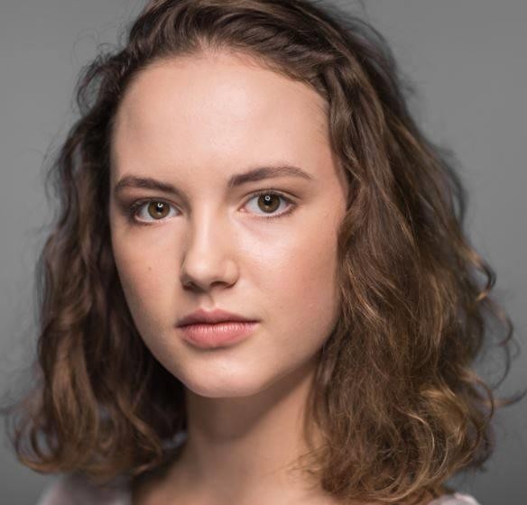 Martyna Byczkowska, młoda polska aktorka, uśmiechnięta w swobodnym, stylowym stroju, na delikatnie rozmytym tle, ukazująca jej naturalny urok.