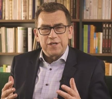 Maciej Orłoś prowadzący szkolenie z wystąpień publicznych, gestykulujący i przemawiający do publiczności.