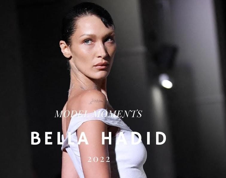 Bella Hadid uśmiechnięta, z telefonem w dłoni, symbolizująca jej silną obecność i interakcję z fanami w mediach społecznościowych.